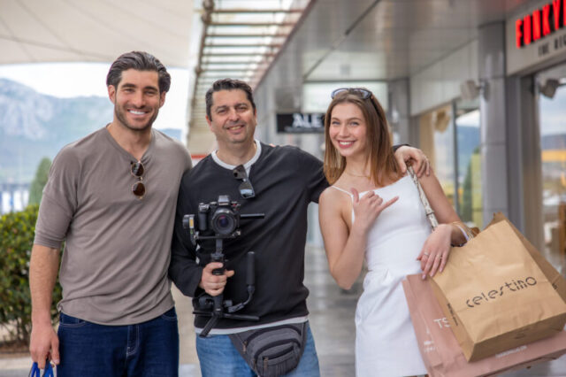 Man walking out of fashion retail store with shopping bag during commercial lifestyle video shoot in Greece